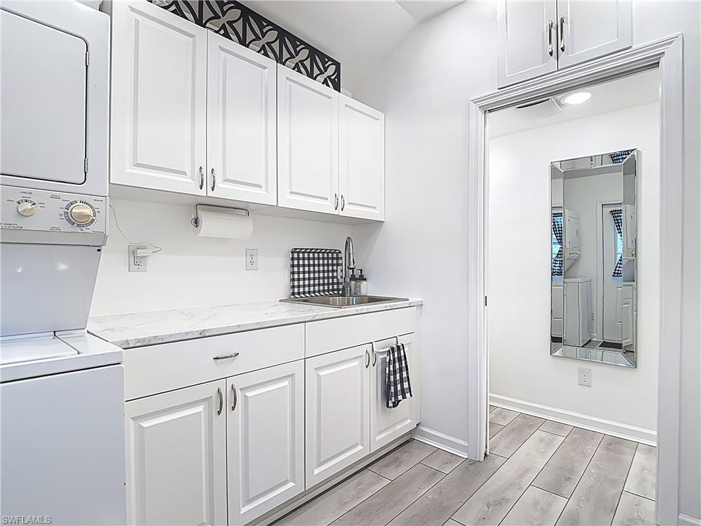 Laundry area featuring wood tiled floors and stacked washer / drying machine
