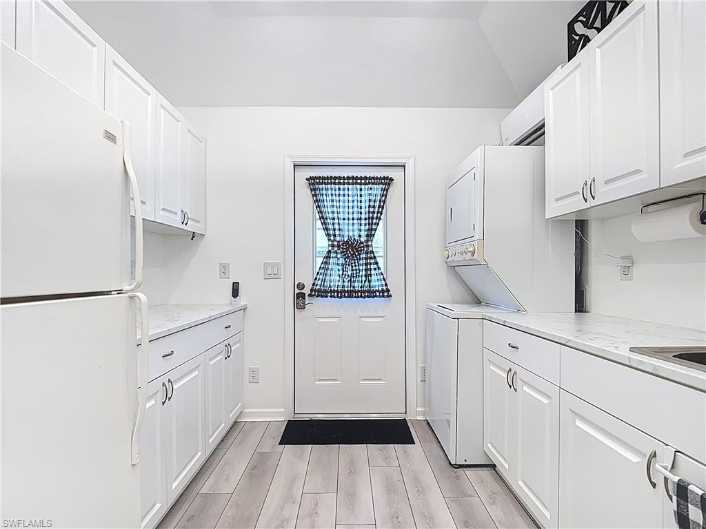 Washroom with wood tiled floors, stacked washing machine and dryer, and cabinet space