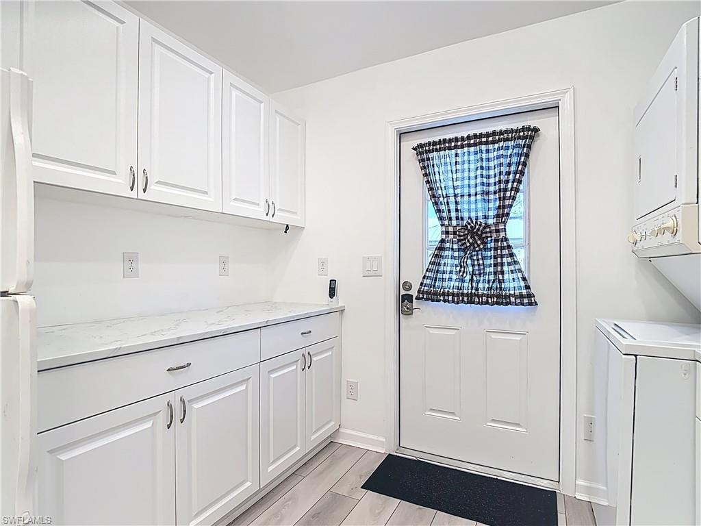 Washroom with stacked washer and clothes dryer and wood tiled floors