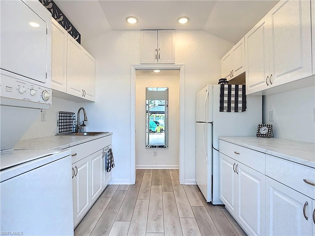 Kitchen with white cabinetry, light wood-type flooring, freestanding refrigerator, lofted ceiling, and recessed lighting