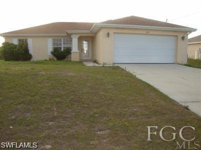 View of front of house featuring concrete driveway, a front yard, a garage, and stucco siding