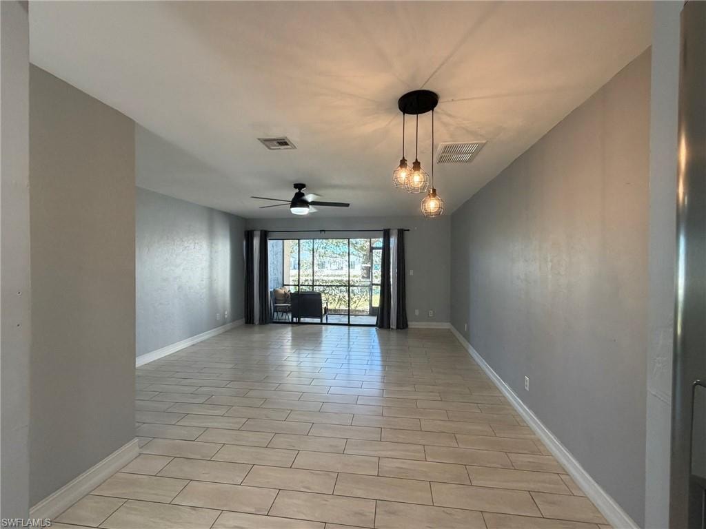 Empty room featuring ceiling fan and baseboards