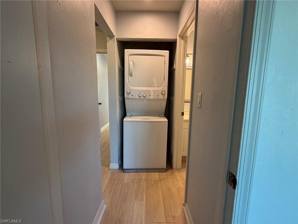 Hallway featuring estacked washer and dryer and light wood-style floors