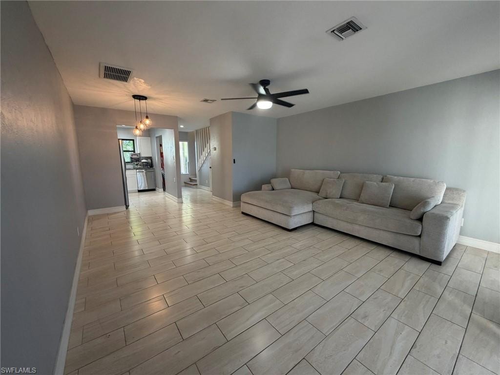 Living area with stairway, a ceiling fan, and wood finish floors