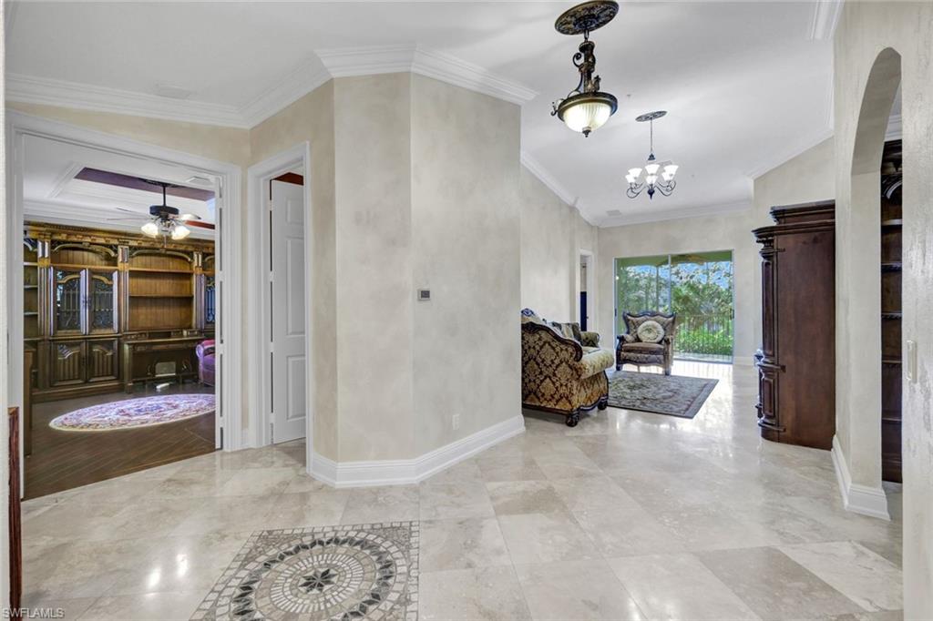 Hall with crown molding and a chandelier