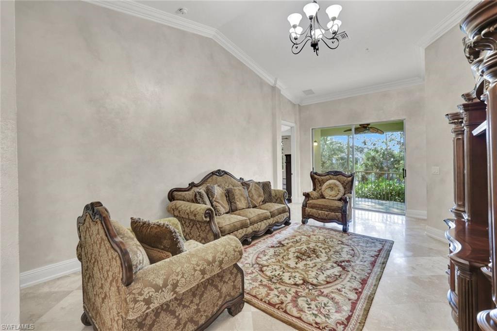 Living room with ornamental molding, a chandelier, and lofted ceiling