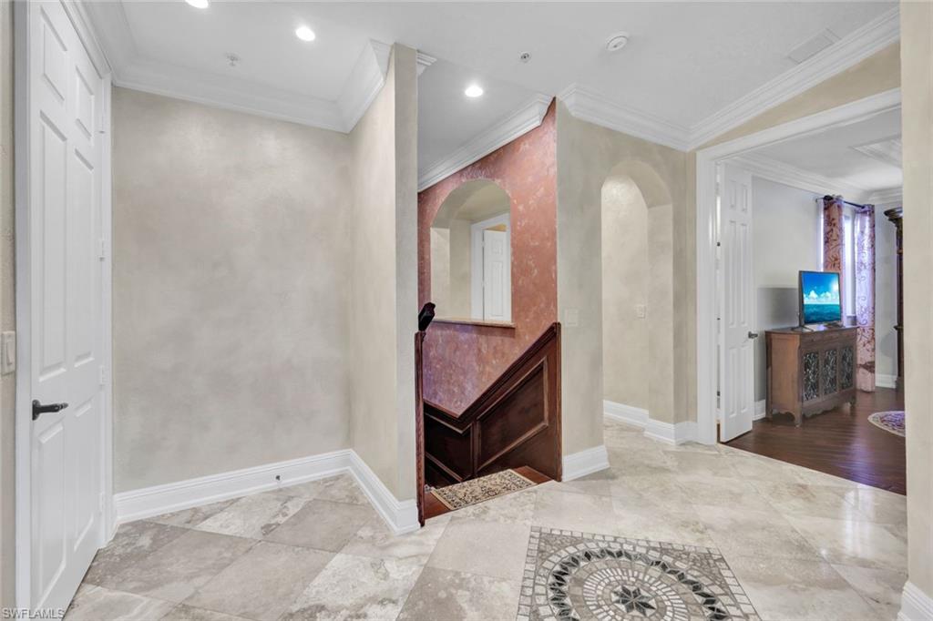 Corridor featuring crown molding, arched walkways, and recessed lighting