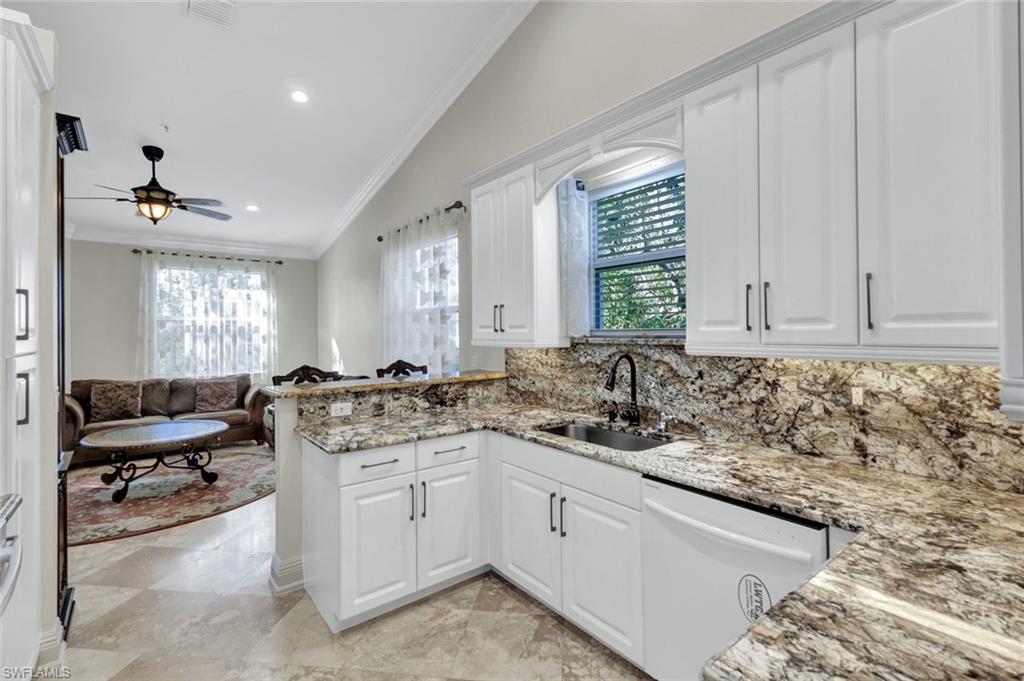 Kitchen with crown molding, white cabinets, vaulted ceiling, white dishwasher, and open floor plan