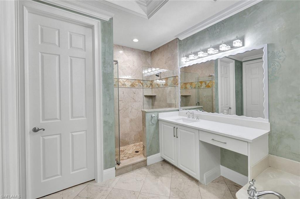 Bathroom with vanity, crown molding, a shower stall, and light marble finish floors
