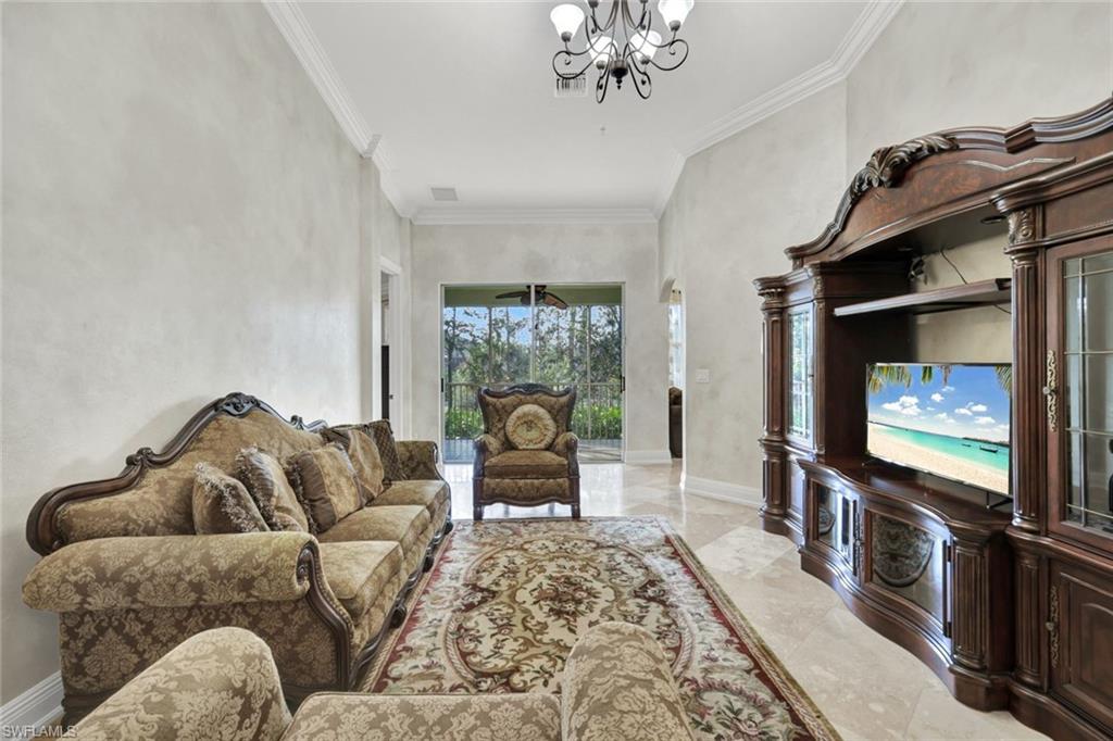 Living room with light marble finish floors, crown molding, and a chandelier