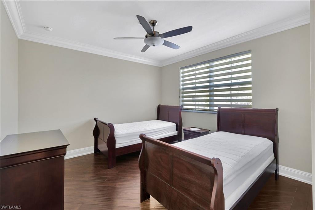 Bedroom featuring dark wood finished floors, crown molding, and ceiling fan