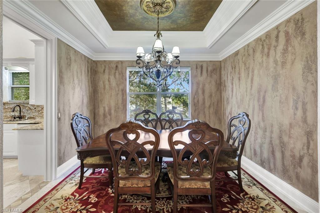 Dining room featuring crown molding, a raised ceiling, and a chandelier