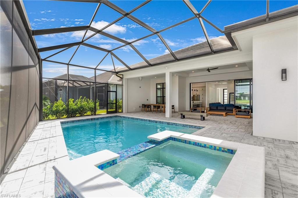 View of swimming pool with a sunroom, a pool with connected hot tub, a patio, an outdoor hangout area, and glass enclosure