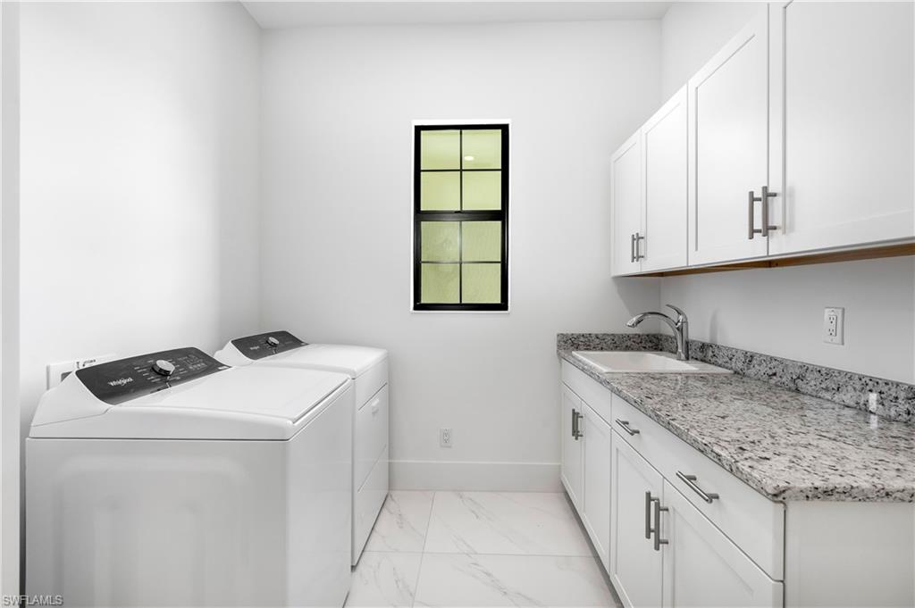 Washroom with light marble finish flooring, cabinet space, and washing machine and clothes dryer