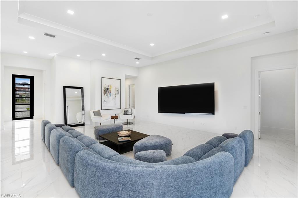 Living area with light marble finish floors, recessed lighting, and a raised ceiling