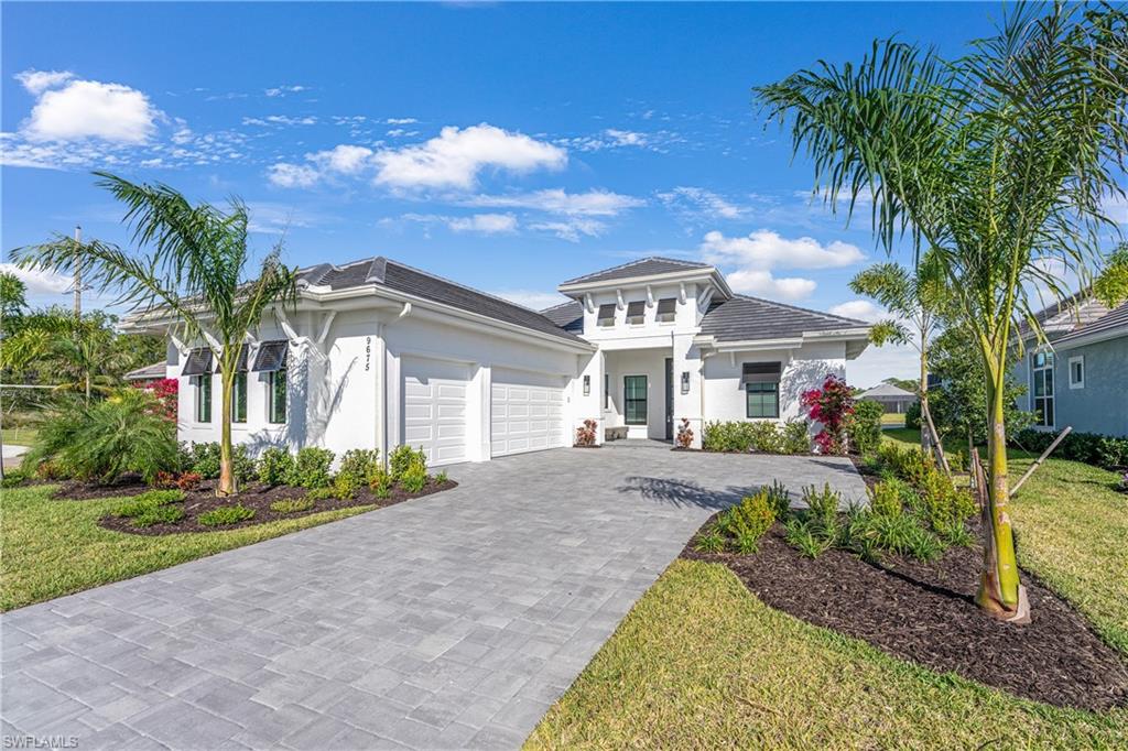 View of front facade with stucco siding, decorative driveway, an attached garage, and a front lawn
