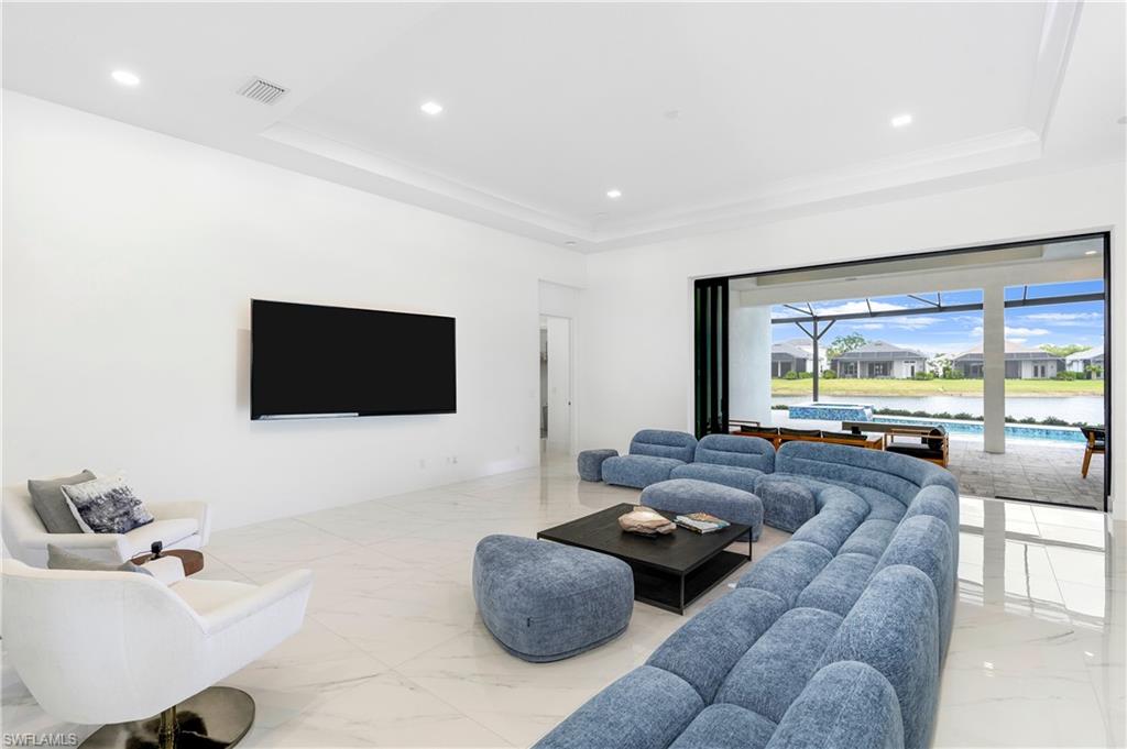 Living area featuring a sunroom, a raised ceiling, recessed lighting, and light marble finish floors