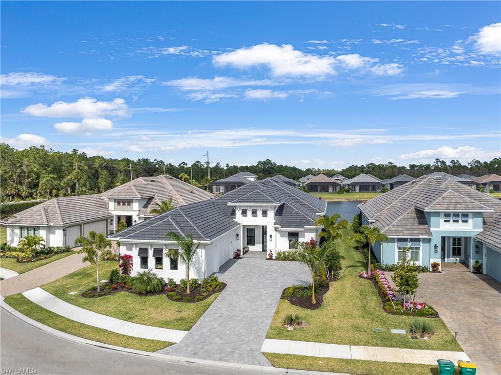 View of front of house with a residential view, decorative driveway, stucco siding, an attached garage, and a front lawn