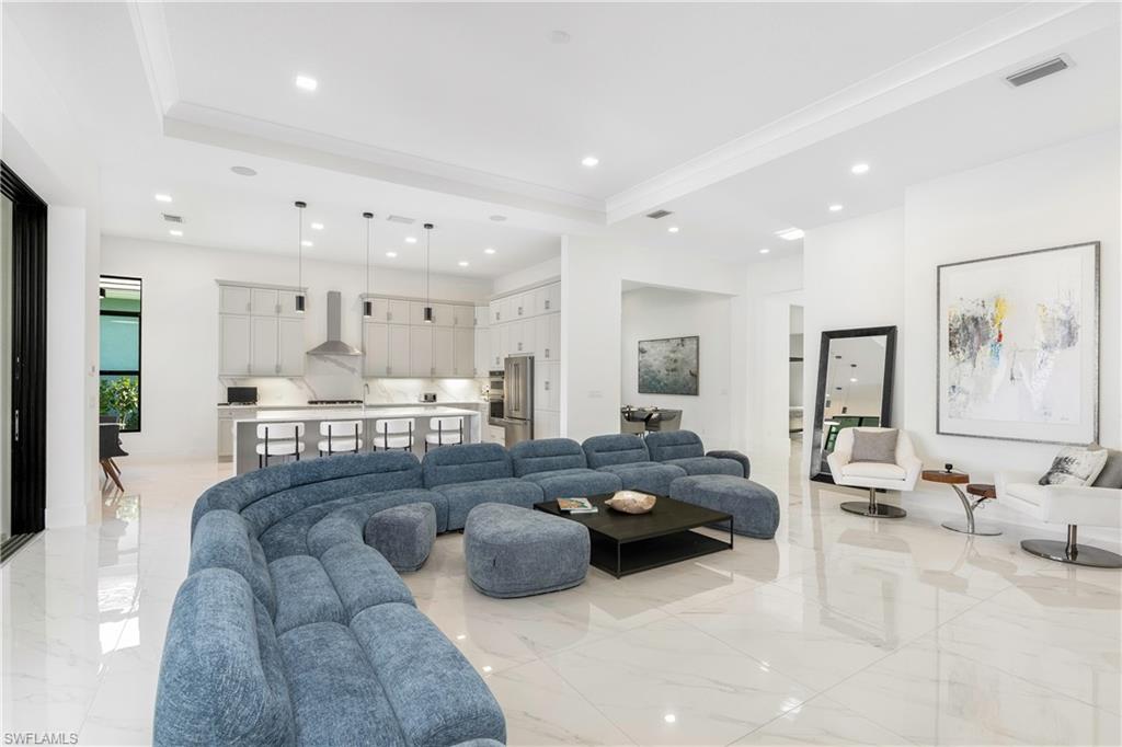 Living area featuring recessed lighting, light marble finish flooring, and crown molding