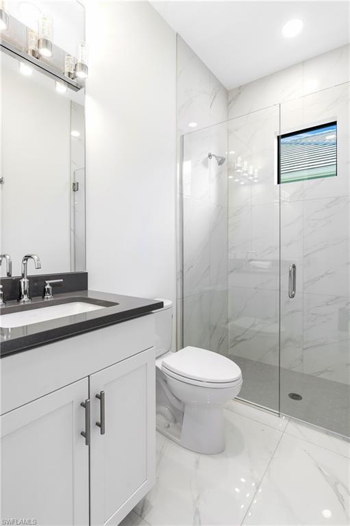 Bathroom with light marble finish floors, vanity, a marble finish shower, and recessed lighting