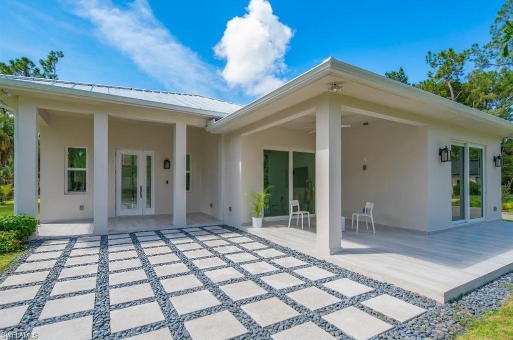 Back of house featuring stucco siding, a patio, a metal roof, and french doors