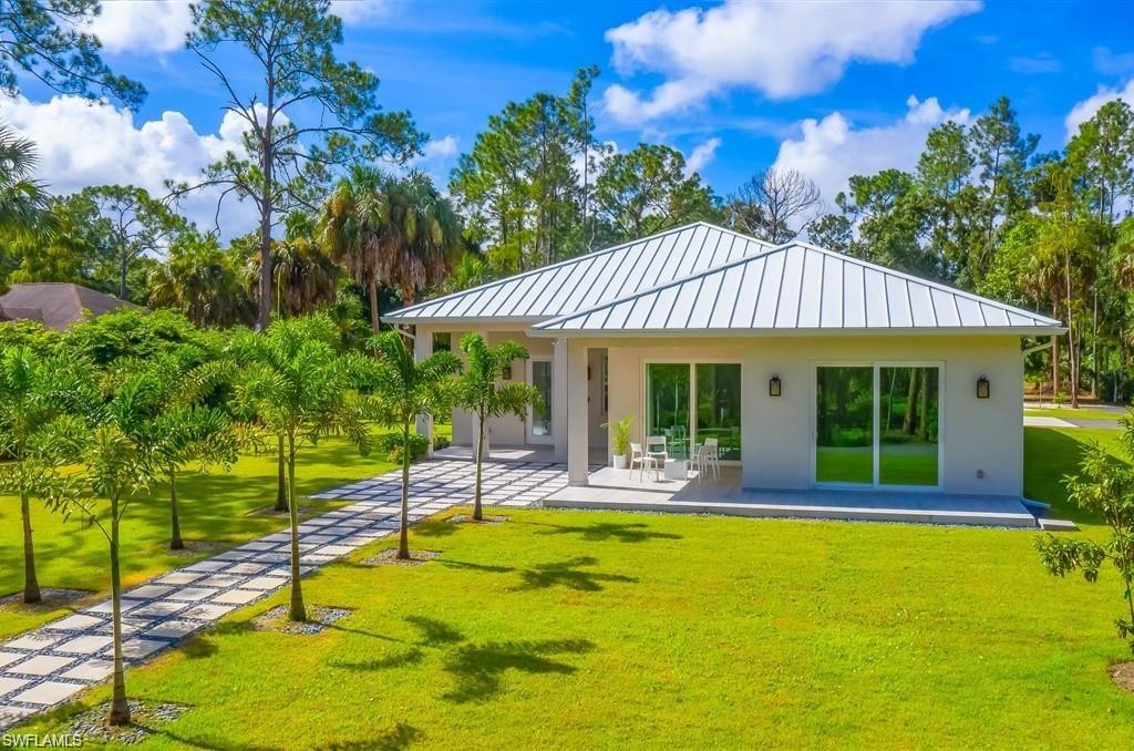 Back of house featuring a standing seam roof, a yard, a patio, a metal roof, and stucco siding