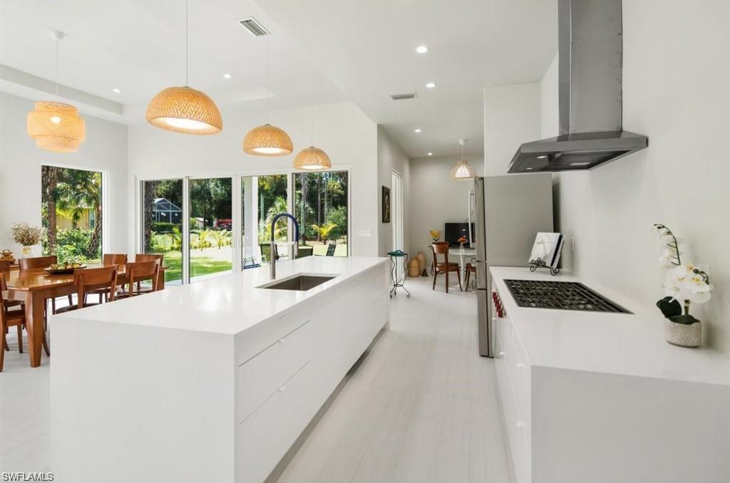 Kitchen featuring pendant lighting, range hood, modern cabinets, light stone counters, and recessed lighting