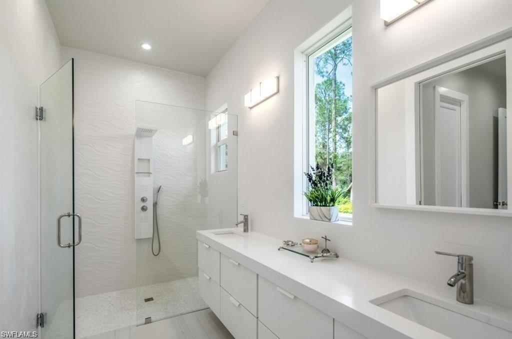 Full bath with double vanity and a shower stall