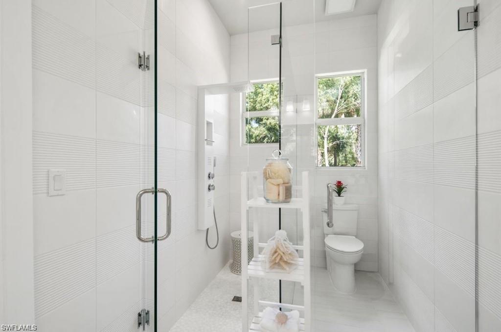 Bathroom featuring a shower stall and tile walls