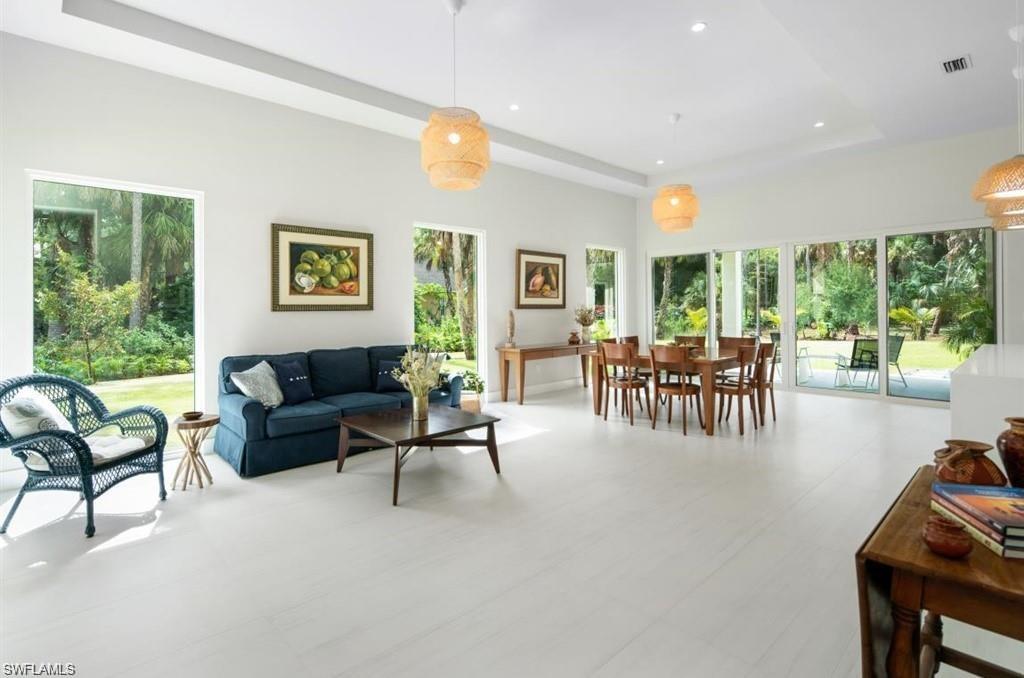 Living area featuring a tray ceiling, recessed lighting, a high ceiling, and tile patterned floors