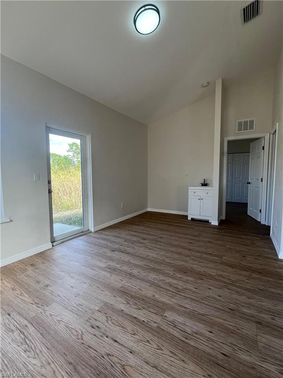 Unfurnished room with light wood-type flooring and high vaulted ceiling