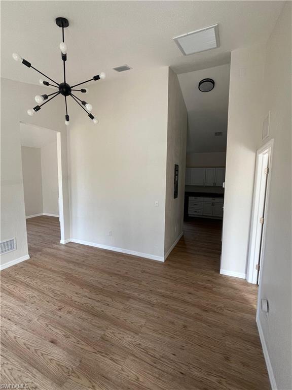 Empty room featuring wood finished floors and a chandelier