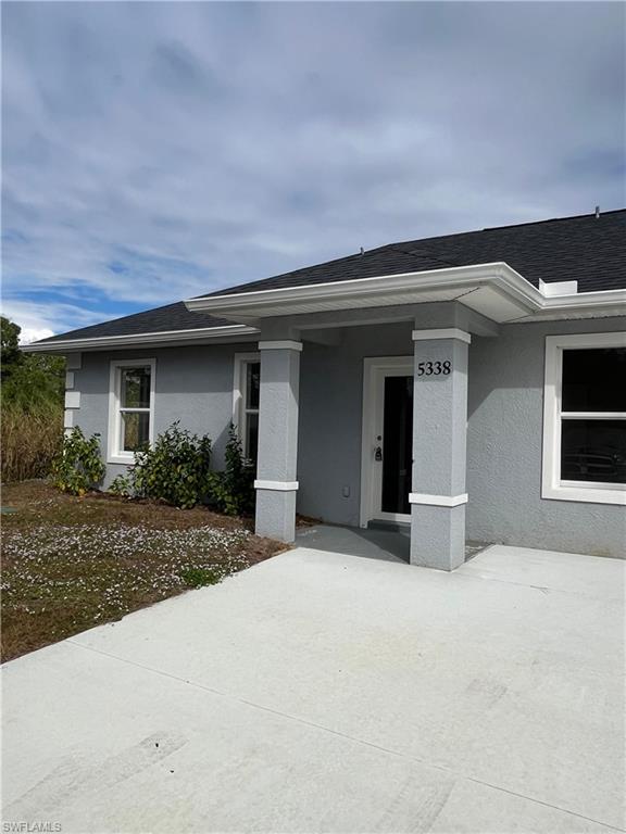 Entrance to property featuring stucco siding and a shingled roof