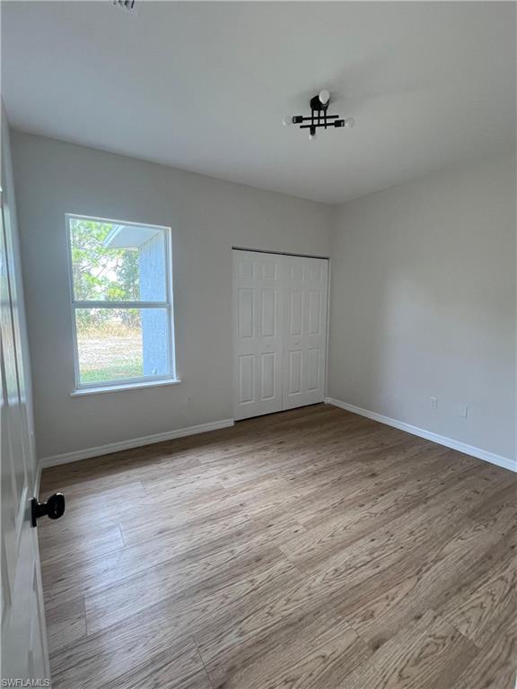 Unfurnished bedroom featuring light wood-style floors and a closet