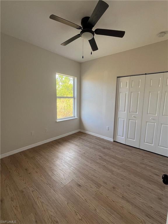 Unfurnished bedroom with a closet, wood finished floors, and ceiling fan