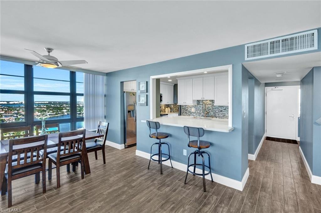 Kitchen with a kitchen bar, tasteful backsplash, stainless steel fridge with ice dispenser, white cabinets, and a ceiling fan