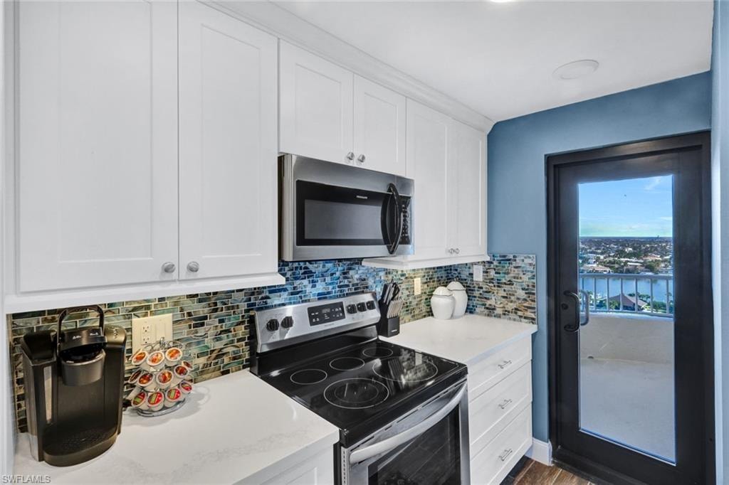 Kitchen with appliances with stainless steel finishes, white cabinetry, and backsplash