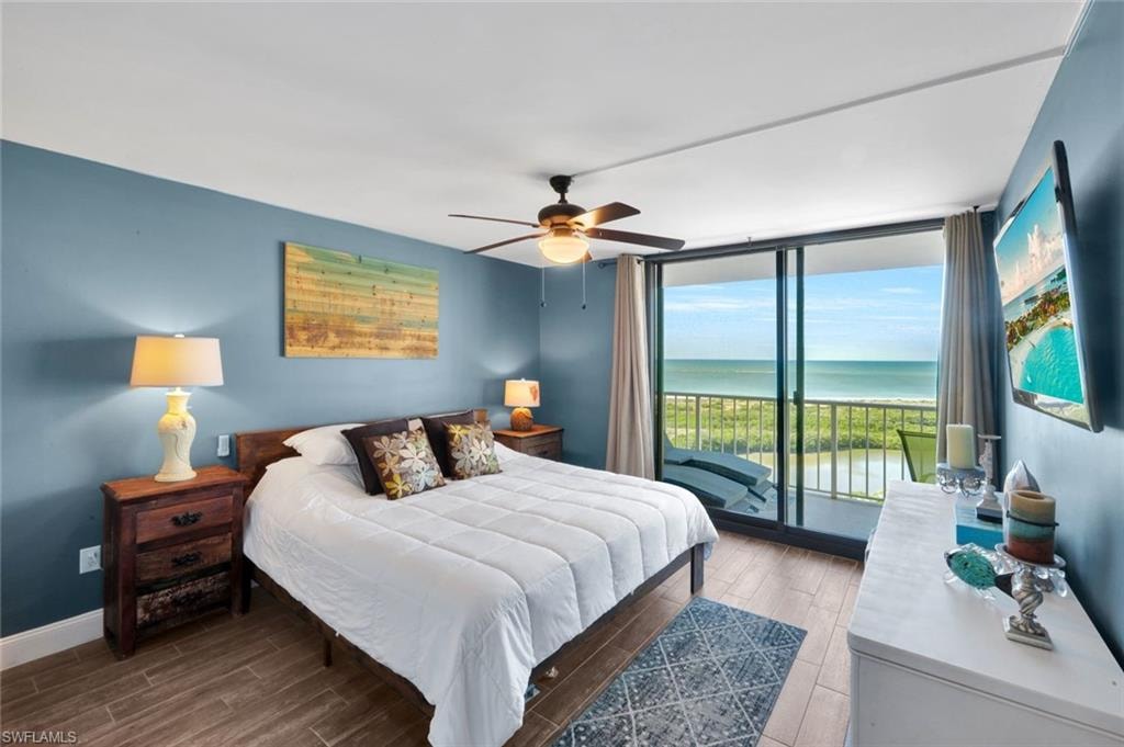 Bedroom with wood tiled floors, expansive windows, access to outside, and ceiling fan