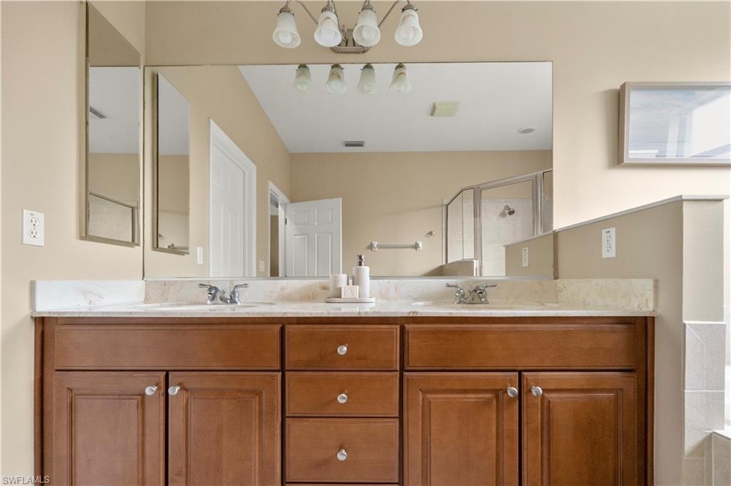 Full bath with double vanity, a stall shower, and a relaxing tiled tub