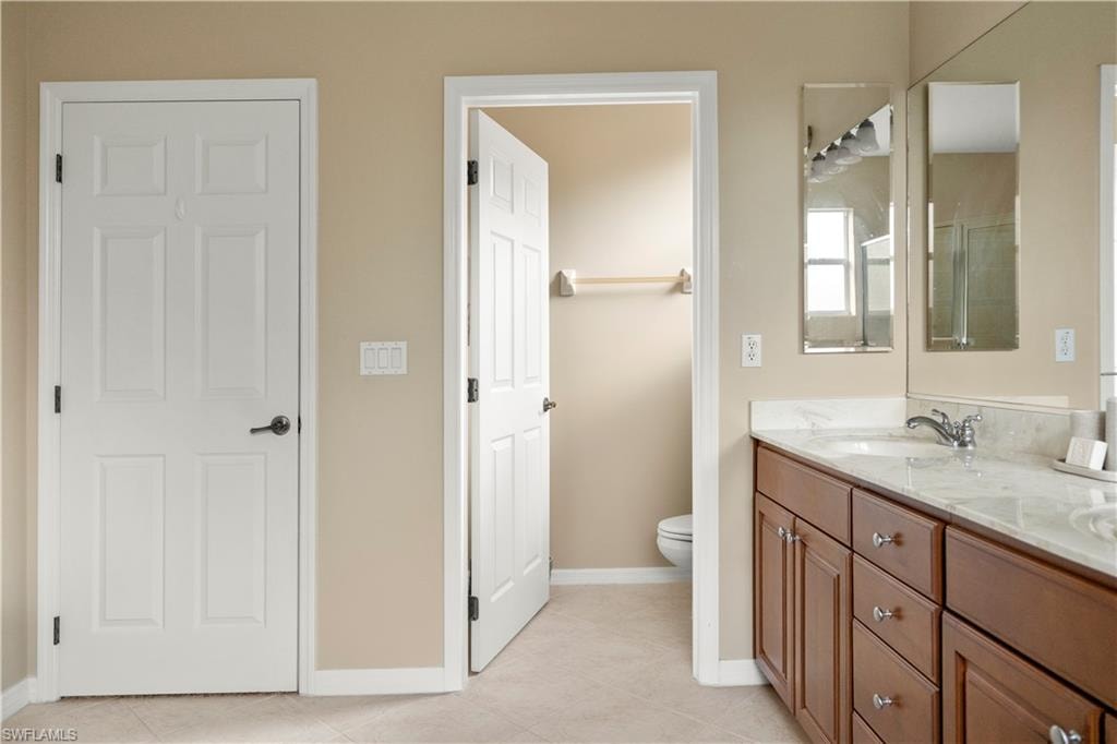 Bathroom with double vanity and light tile patterned floors