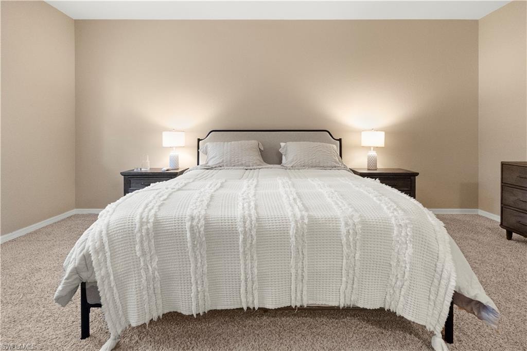 Bedroom featuring light carpet and baseboards