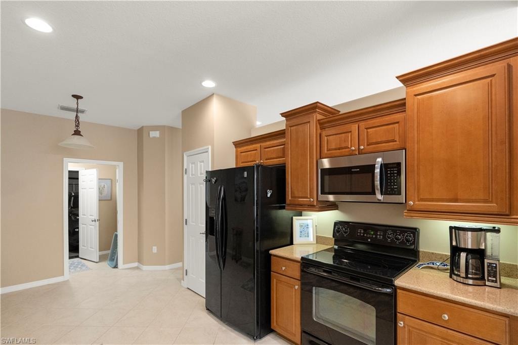 Kitchen featuring black appliances, decorative light fixtures, brown cabinets, recessed lighting, and light tile patterned flooring