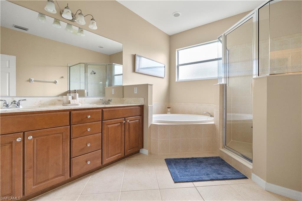 Full bath with a shower stall, double vanity, light tile patterned floors, and a bath