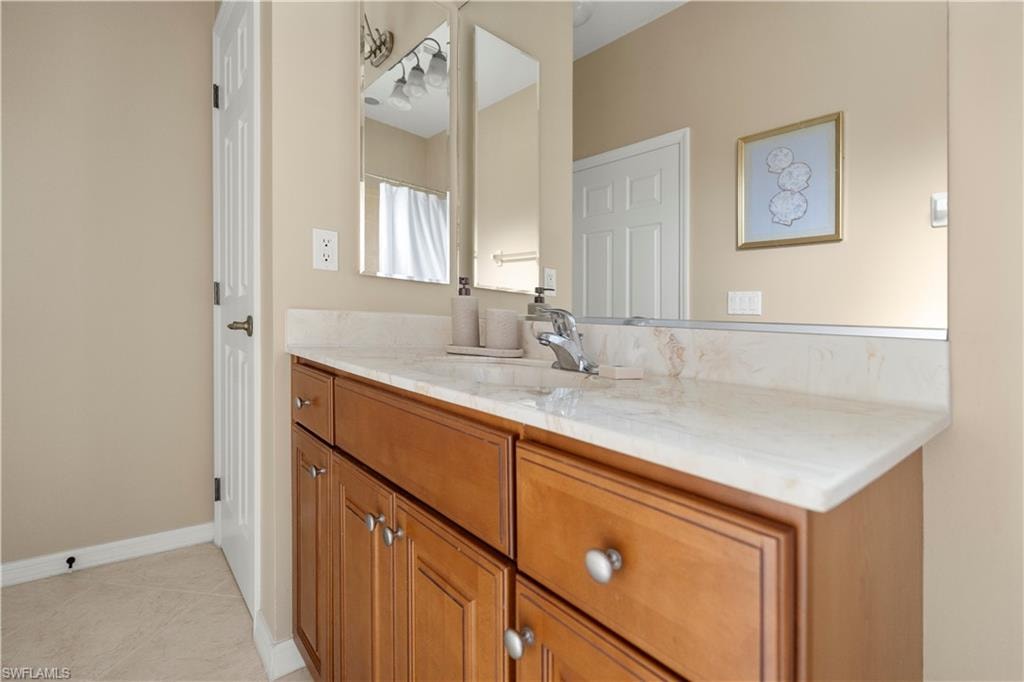 Bathroom with vanity, light tile patterned floors, and curtained shower