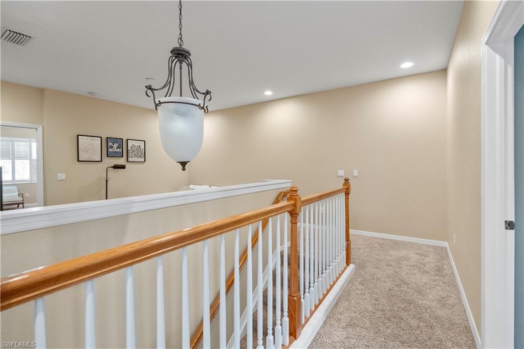 Hallway with light carpet, an upstairs landing, and recessed lighting