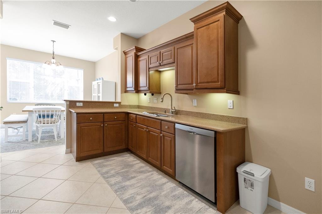 Kitchen with stainless steel dishwasher, brown cabinets, pendant lighting, a chandelier, and recessed lighting