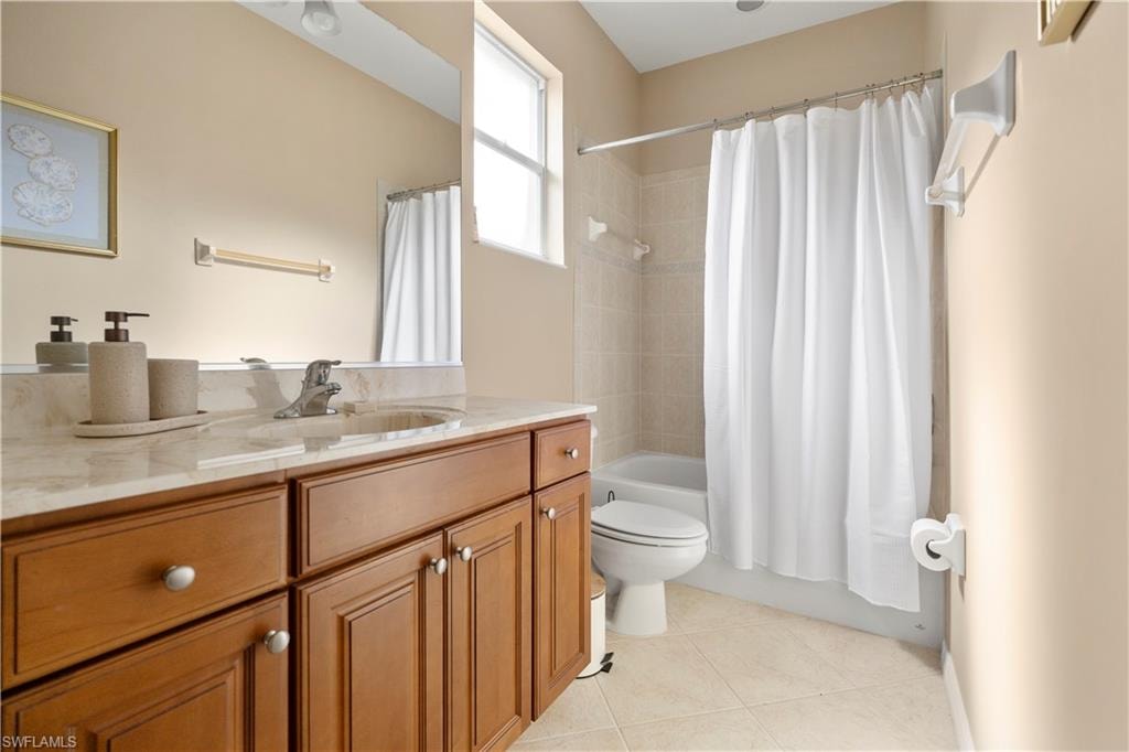 Bathroom featuring vanity, shower / bath combo, and light tile patterned floors