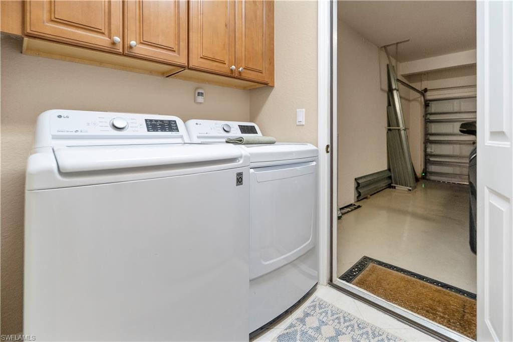 Washroom featuring washer and dryer, cabinet space, and concrete floors