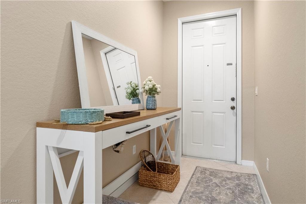 Doorway to outside featuring tile patterned flooring and a textured wall