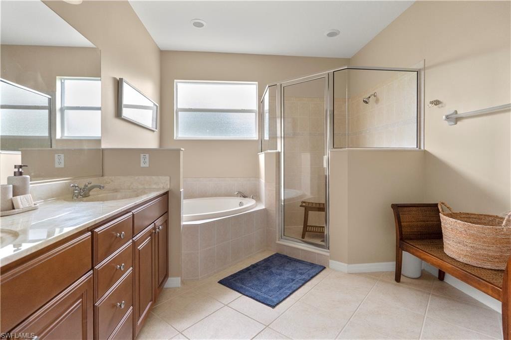 Full bath with double vanity, a garden tub, a shower stall, and light tile patterned floors
